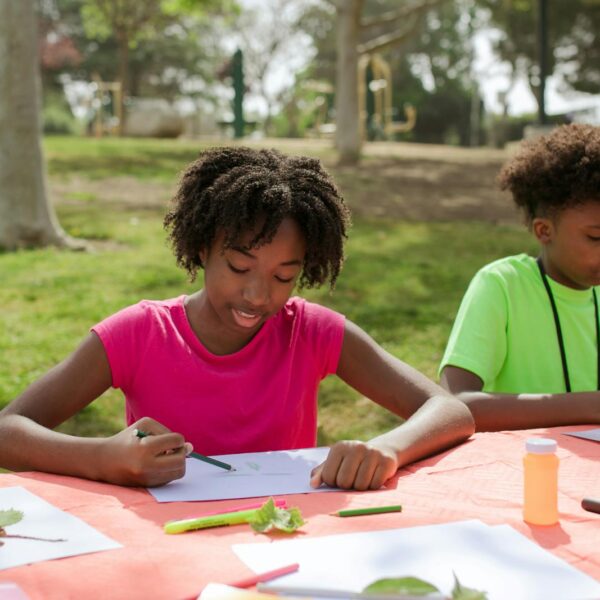 A Young Girl and Boy Writing and Drawing on Papers at the Table