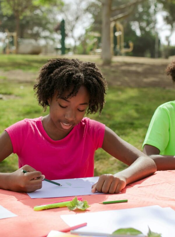 A Young Girl and Boy Writing and Drawing on Papers at the Table